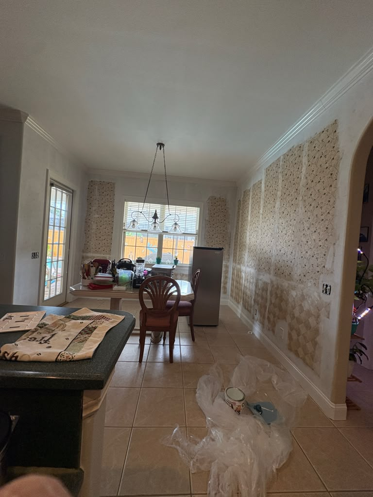 Open kitchen and dining before — patterned wallpaper being stripped from the walls